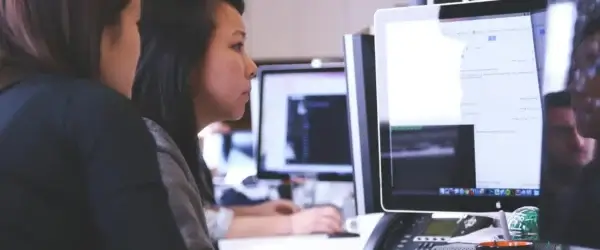 two women sitting in front of computer monitor