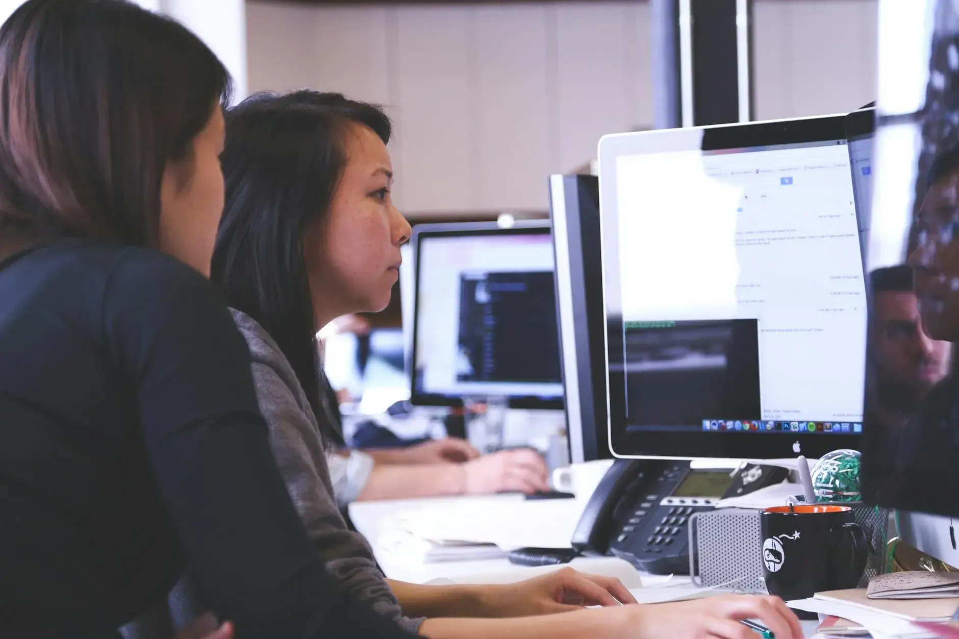 two women sitting in front of computer monitor
