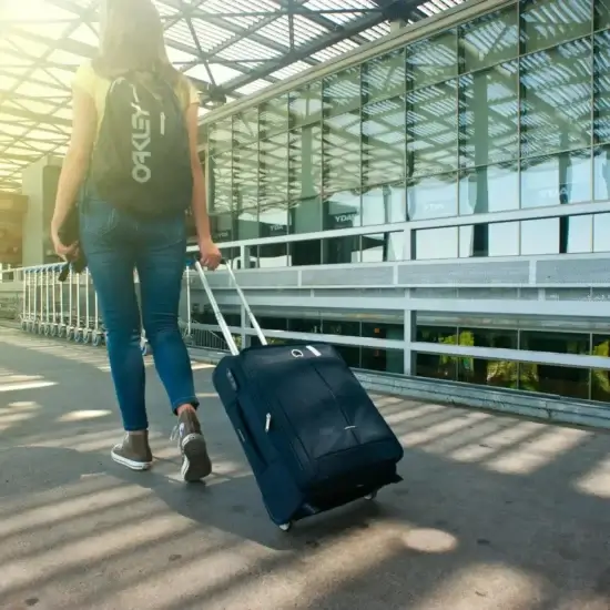 woman walking on pathway while strolling luggage