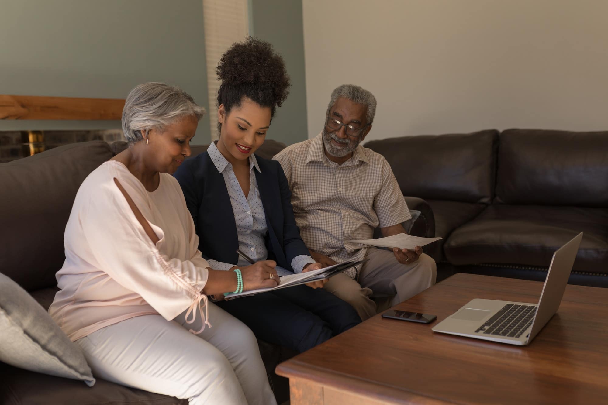 Woman signing property contract with real estate planning agent and senior man in living room at home