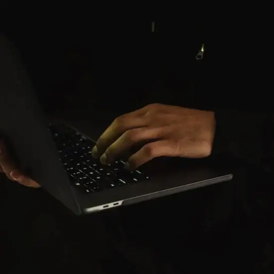 crop unrecognizable man using laptop in darkness