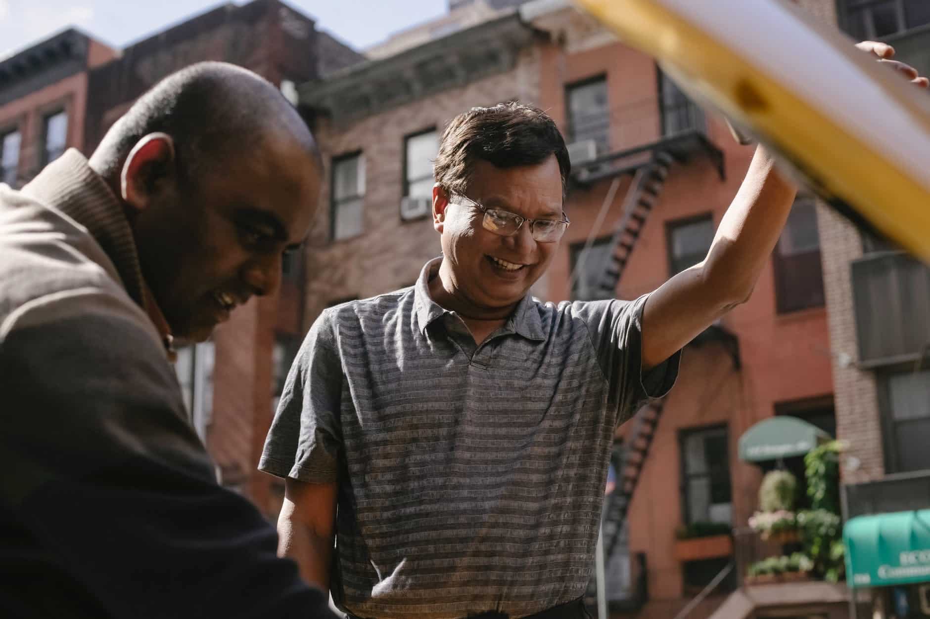 cheerful ethnic man repairing broken car with friend