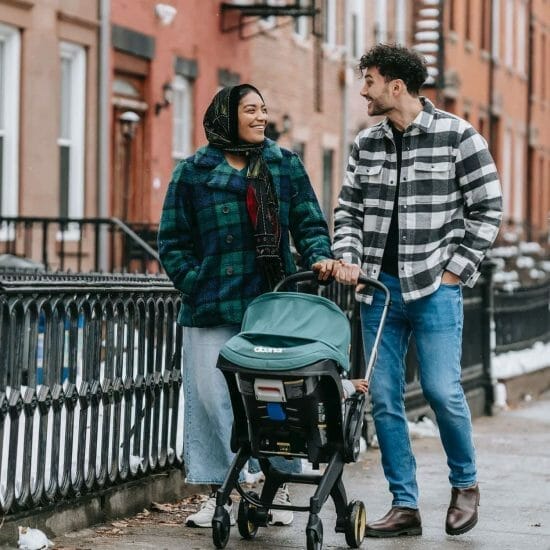 happy multiethnic parents walking with baby stroller