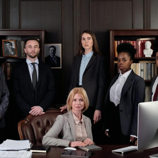 Diverse group of professionals in corporate attire posing confidently in an office environment.