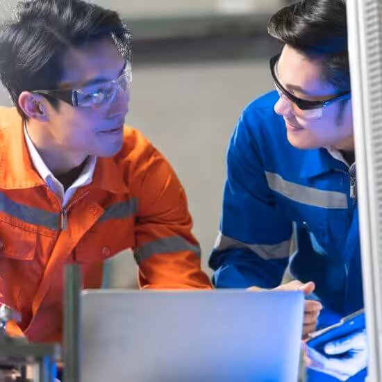 Engineers collaborating on factory machinery.